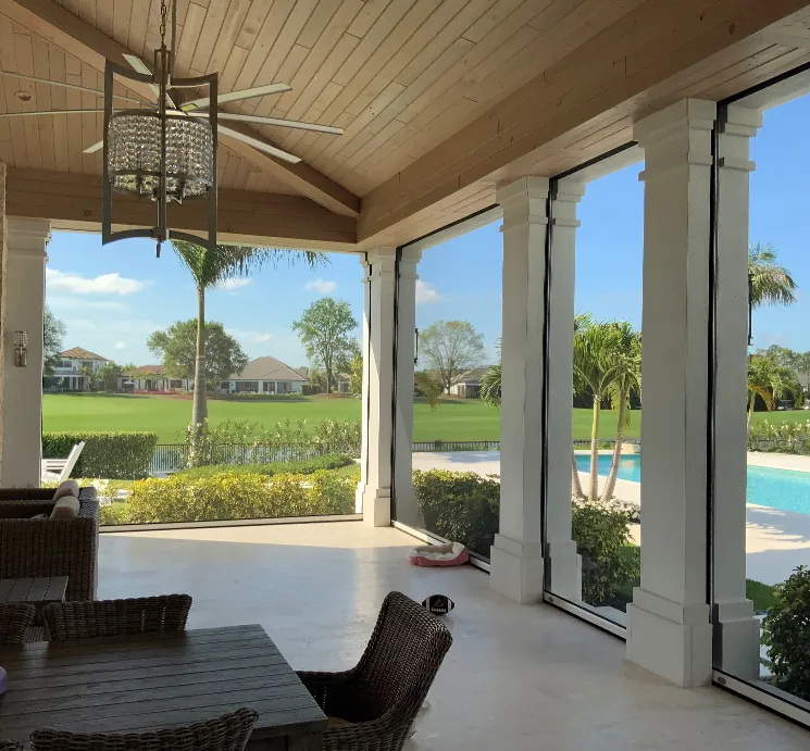 Covered patio with screens between columns overlooking a pool and golf course