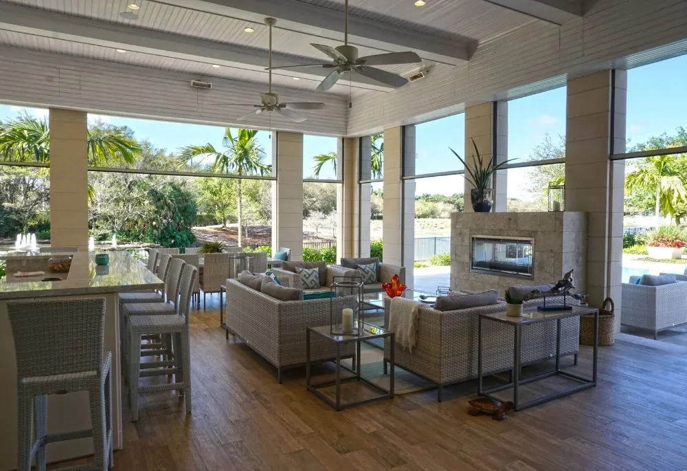 Large screened outdoor living room with sofas, bar seating and a fireplace